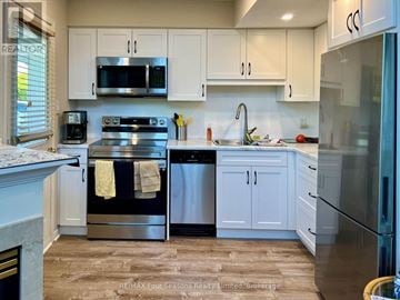 Collingwood triplex for rent - A kitchen with white cabinets and a stainless steel dishwasher.