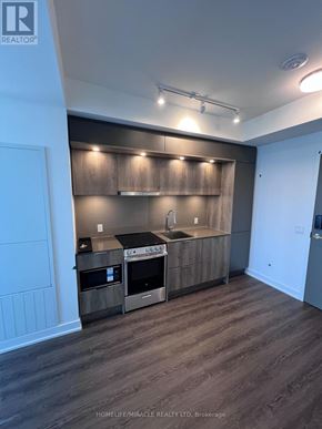 Mississauga (City Centre) condo for rent - A kitchen with wooden cabinets and a black stove top oven.
