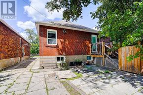 Toronto (Broadview North) apartment for rent - A red brick house with a green door and a window is surrounded by a wooden fence.