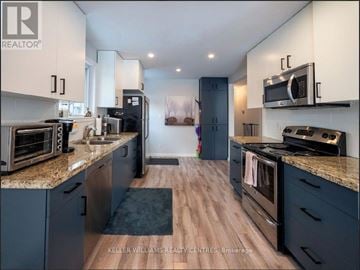 Newmarket (Huron Heights-Leslie Valley) apartment for rent - A modern kitchen with dark blue cabinets and stainless steel appliances.