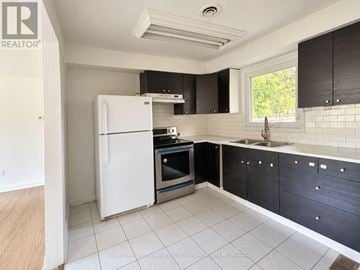 Vaughan (Maple) apartment for rent - A kitchen with a white fridge, black cabinets, and a window.