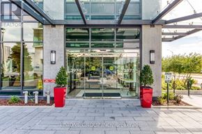 Mississauga (City Centre) condo for rent - The front of a building with a glass door and two red planters on either side.