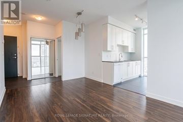 Mississauga (Creditview) condo for rent - A spacious room with wooden floors and white walls, featuring a kitchen area with white cabinets and a countertop.