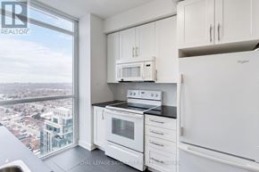 Mississauga (Creditview) condo for rent - A kitchen with white cabinets and appliances, a window with a view of a cityscape.