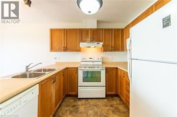Waterloo townhouse for rent - A kitchen with wooden cabinets and a white stove top oven.