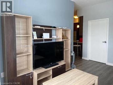 Waterloo condo for rent - A living room with a television and a wooden cabinet.