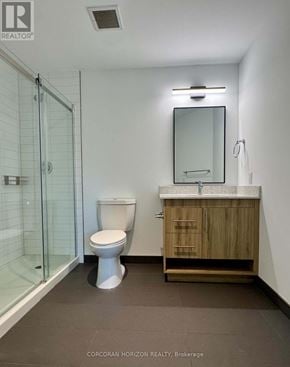 Kitchener condo for rent - A white toilet sits in a small bathroom with a wooden cabinet and a glass shower door.