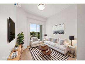 Langley apartment for rent - A living room with a white couch, a coffee table, and a flat-screen TV mounted on the wall.