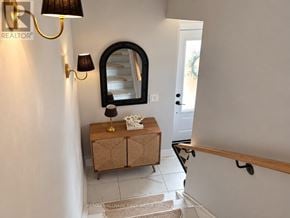 Oshawa (O'neill) multi-family for rent - A hallway with a mirror, two wall lamps, and a wooden bench.