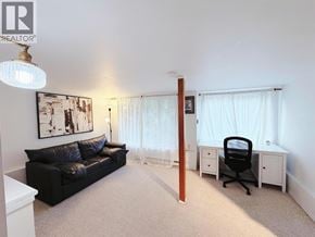 Vancouver apartment for rent - A black leather couch sits in a well lit room with a white desk and chair.