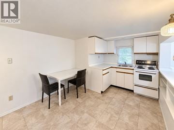 Vancouver apartment for rent - A kitchen with white cabinets and a table with two chairs.