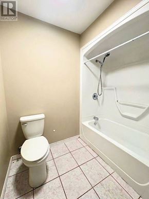 Ottawa apartment for rent - A white toilet sits next to a white bathtub in a small bathroom.