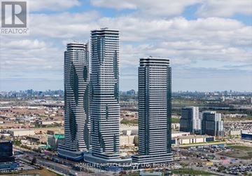 Vaughan (Vaughan Corporate Centre) condo for rent - Two tall buildings are under construction with a sign that says "HOMELIFE/MIRACLE REALTY LTD Brokerage".