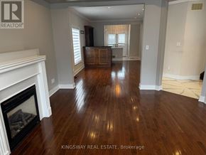 Brampton (Credit Valley) apartment for rent - A Kingsway Real Estate Brokerage sign is displayed in a spacious room with hardwood floors and a fireplace.