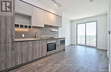 Vaughan (Vaughan Corporate Centre) condo for rent - A kitchen with wooden cabinets and a microwave built into the counter.