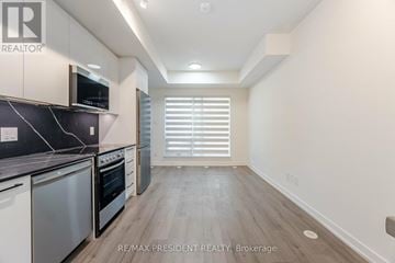 Toronto (Clanton Park) townhouse for rent - A kitchen with white cabinets and a black counter top.