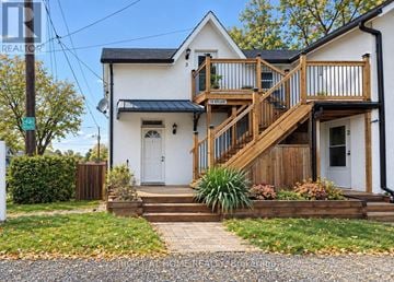 Oshawa (O'neill) triplex for rent - A white house with a wooden deck and stairs leading to the front door.