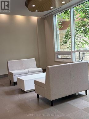 Markham (Unionville) condo for rent - A white couch and ottoman are in a room with a large window.
