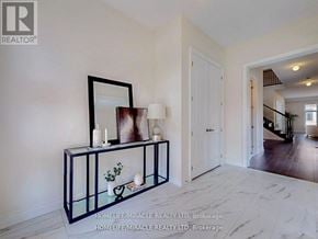 Whitchurch-Stouffville (Ballantrae) apartment for rent - A room with a white wall and a black and white console table with a mirror and a vase of flowers on it.