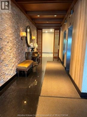 Windsor condo for rent - A hallway with a stone wall and a mirror on the left side.