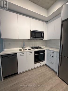 Toronto (Kensington-Chinatown) condo for rent - A kitchen with white cabinets and a black dishwasher.