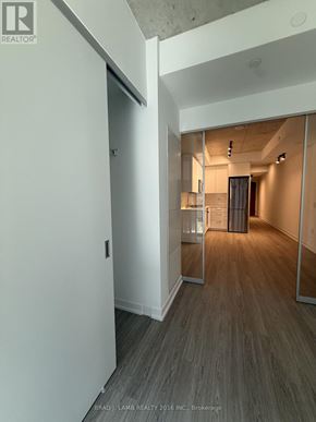 Toronto (Kensington-Chinatown) condo for rent - A hallway with a wooden floor and white walls.