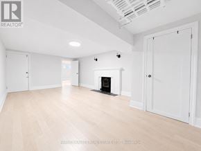 Toronto (Lawrence Park South) multi-family for rent - A spacious room with a fireplace and wooden flooring.