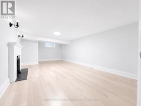 Toronto (Lawrence Park South) multi-family for rent - A spacious room with wooden flooring and white walls.