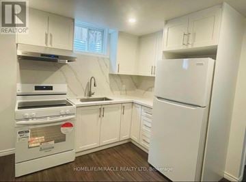 Ajax (Central East) apartment for rent - A white kitchen with a refrigerator, sink, and cabinets.