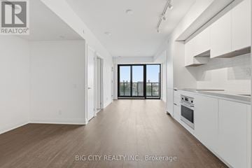 Toronto (Thorncliffe Park) condo for rent - A spacious kitchen with white cabinets and a view of the city through the windows.