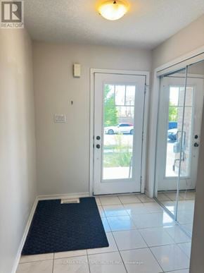 Brantford townhouse for rent - A hallway with a black doormat and white walls.