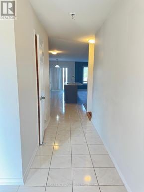 Brantford townhouse for rent - A long hallway with white walls and tiled floors.
