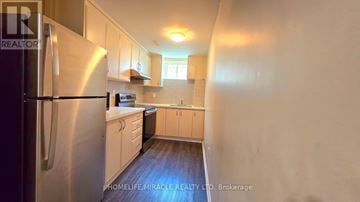 Brampton (Northwest Brampton) apartment for rent - A kitchen with a refrigerator on the left and a counter with a sink and a window in the background.