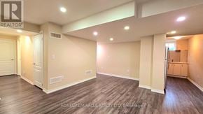 Brampton (Northwest Brampton) apartment for rent - A spacious room with wooden flooring and beige walls, with a door on the left and a cabinet on the right.