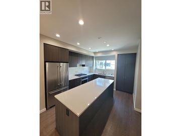 Pitt Meadows townhouse for rent - A modern kitchen with dark wood cabinets and stainless steel appliances.