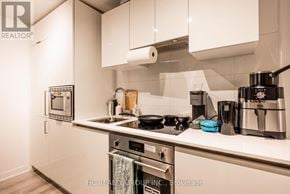 Toronto (Kensington-Chinatown) condo for rent - A modern kitchen with stainless steel appliances and white cabinets.