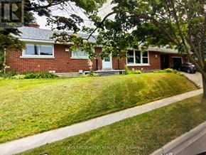 Kitchener apartment for rent - A house with a red brick exterior and a white door is surrounded by a green lawn.