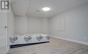 Ajax (Northeast Ajax) apartment for rent - A bedroom with a bed, wooden flooring, and a white wall.