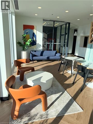 Kitchener condo for rent - A modern living room with a blue sofa and orange chairs.
