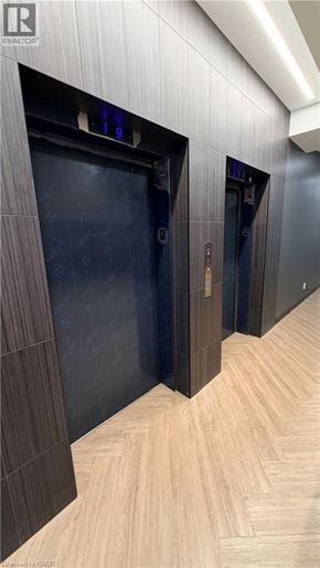 Kitchener condo for rent - A hallway with two elevators and a wood floor.