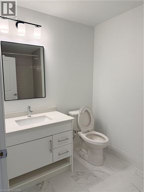 Kitchener condo for rent - A white bathroom with a toilet, sink, and mirror.