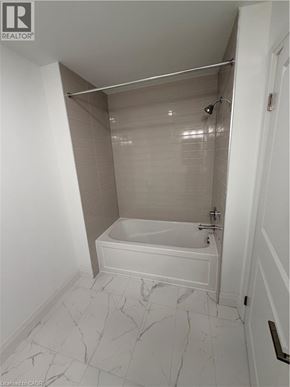 Kitchener condo for rent - A white bathroom with a tub and shower.