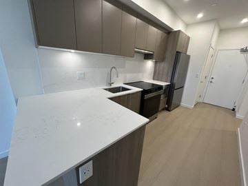 Surrey apartment for rent - A kitchen with a white counter top and brown cabinets.