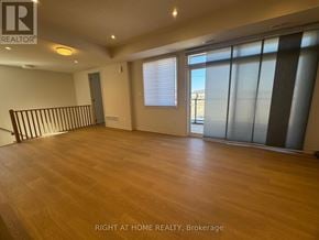 Kawartha Lakes (Lindsay) multi-family for rent - A spacious room with wooden flooring and large windows.