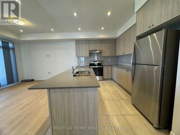 Kawartha Lakes (Lindsay) multi-family for rent - A modern kitchen with a stainless steel refrigerator and wooden cabinets.