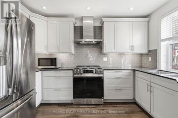 Hamilton (Corktown) multi-family for rent - A modern kitchen with white cabinets and stainless steel appliances.
