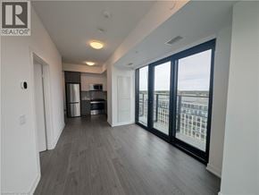 Kitchener condo for rent - A spacious room with a view of the city through large windows.