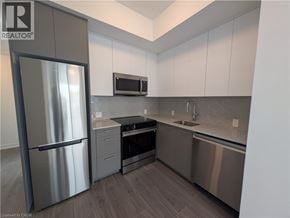Kitchener condo for rent - A modern kitchen with stainless steel appliances and white cabinets.