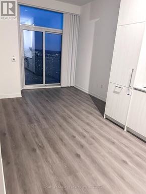 Vaughan (Vaughan Corporate Centre) condo for rent - A room with a sliding glass door and a white fridge.