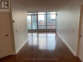 Toronto (Waterfront Communities) condo for rent - A room with wooden floors and a view of the city through the windows.